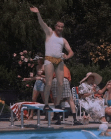 a man in a tank top and leopard print swim trunks is jumping into a swimming pool