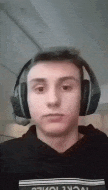 a young man wearing headphones and a black hoodie with the word work on it .