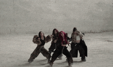 three women with red hair are dancing in front of a concrete wall