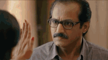 a man with glasses and a mustache is giving a high five to a woman with red nails .