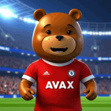 a teddy bear wearing a red avax jersey stands on a soccer field
