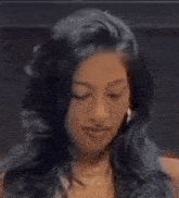 a woman with long black hair and hoop earrings smiles