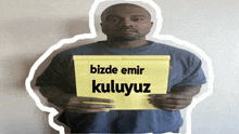 a man holding a piece of paper that says bizde emir kuluyoz