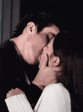 a man and a woman are kissing and the man is holding the woman 's face