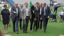 a group of people walking on a field with a man in a wheelchair in the foreground