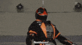 a man in a black and orange outfit is standing underneath a roof
