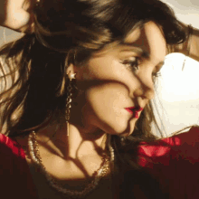 a close up of a woman 's face with a red dress and pearls