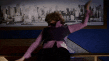 a woman is dancing in front of a picture of a city skyline