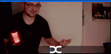 a man in a black shirt is holding a red object in front of a screen that says dc on it