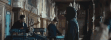 a man in a hoodie is standing in a room with a band playing instruments .