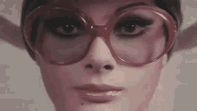 a close up of a woman 's face wearing sunglasses and a hat .