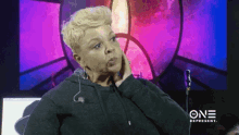a woman is sitting in front of a screen that says one represent on it .