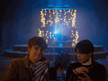 a man and a woman are standing in front of a display of christmas lights