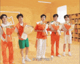 a group of young men are holding bouquets of flowers in front of a yellow wall