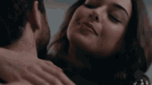 a man and woman are kissing and the woman is looking at the camera .