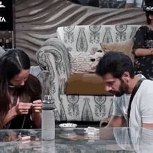 a man and a woman are sitting at a table looking at a cell phone