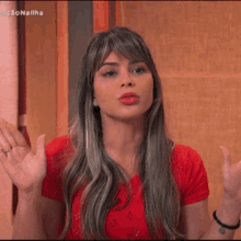a woman in a red shirt is making a funny face with her hands outstretched