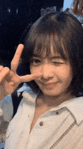 a girl with short hair is making a peace sign with her hand