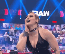 a woman in a black dress is standing in front of a sign that says raw on it