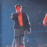 a man is singing into a microphone while another man holds his hand out towards him .