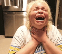 a woman is holding her throat and wearing a shirt that says ucla