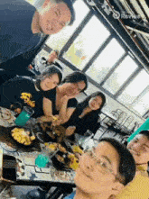 a group of people are posing for a picture while sitting around a table with food .