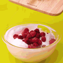 raspberries are being added to a bowl of yogurt