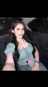 a woman in a green top is taking a selfie in a car