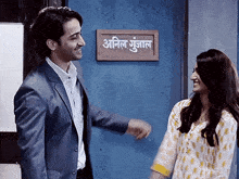 a man and woman are standing in front of a sign that says ' anil ' on it
