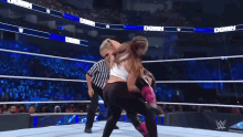 a female wrestler is being lifted in the air by a referee in a wrestling ring