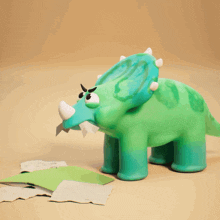 a green dinosaur with horns is standing next to a pile of green paper