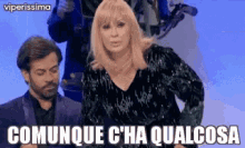 a woman in a black dress is standing next to a man in a suit and says comunque c 'ha qualcosa .