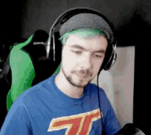 a man with green hair is wearing headphones and a blue t-shirt .