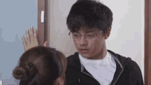 a man wearing glasses is standing next to a woman with her hand on his shoulder