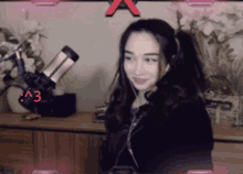 a girl is wearing headphones and smiling in front of a microphone with the letters a3 on it