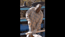 a man in a plaid shirt is cutting a piece of wood with a saw