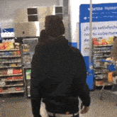 a man in a black hoodie walks through a store with a sign that says betna humor
