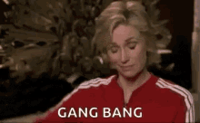 a woman in a red jacket is sitting in front of a peacock and says `` gang bang '' .