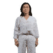 a woman wearing a white shirt and white pants is standing with her hands outstretched