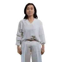 a woman wearing a white shirt and white pants is standing with her hands outstretched