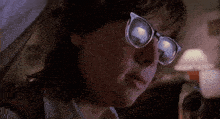 a close up of a person wearing glasses and a white shirt .