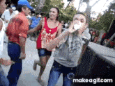 a group of people are dancing in a park and one of them is drinking from a cup