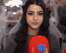 a woman is holding a red boxing glove in her hand