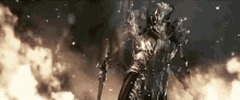 a knight in armor is standing in front of a fire holding a sword .