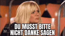 a woman is sitting in a stadium with the words `` du musst bitte nicht danke sagen '' written on the screen .