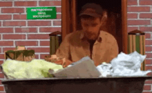 a man sitting in front of a brick wall with a green sign that says no smoking on it