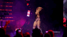 a woman is dancing on a stage with a purple background