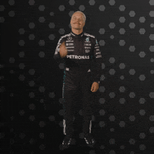 a man in a petronas outfit stands in front of a black background