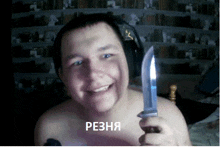 a shirtless man is holding a knife and smiling in front of a library wall