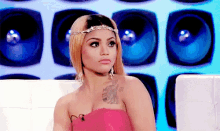 a woman in a pink dress is sitting in front of a speaker wall .